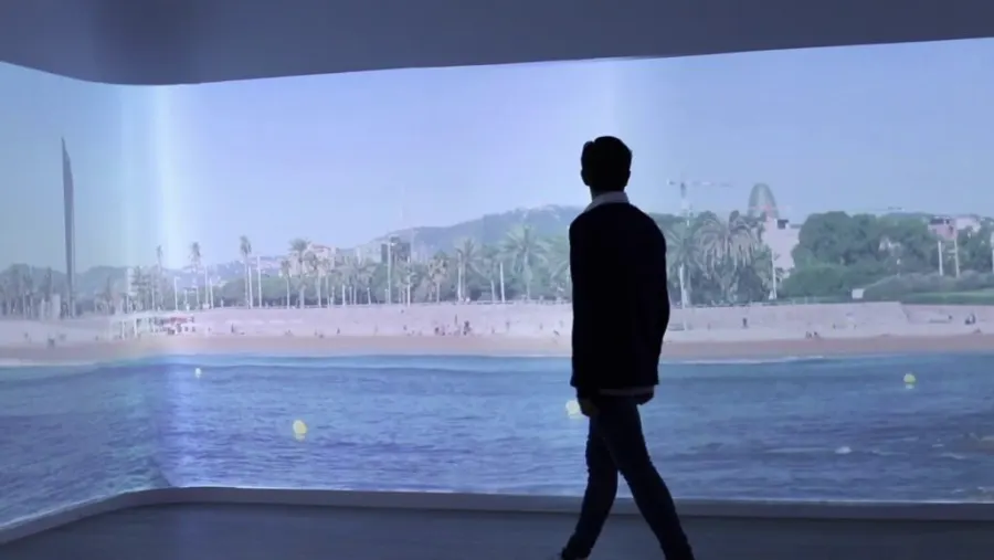 Hombre caminando en una sala con proyección panorámica