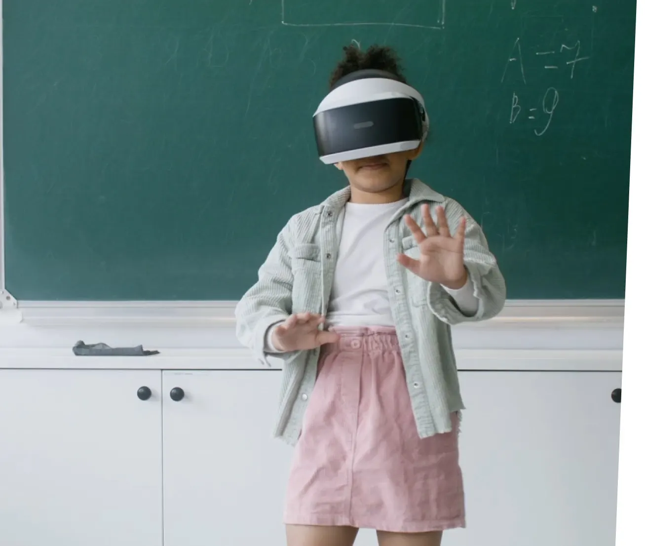Niña usando gafas de realidad virtual frente a la pizarra